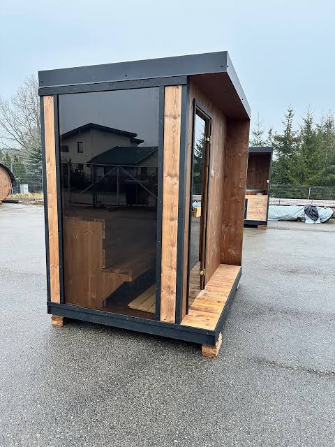 Kompakte Außensauna mit Glasfront und Holzrahmen auf dem Werksgelände